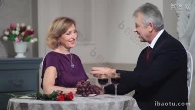 微笑快乐的老夫妇互相喂葡萄，在餐厅庆祝<strong>周年庆</strong>成熟夫妇浪漫的约会